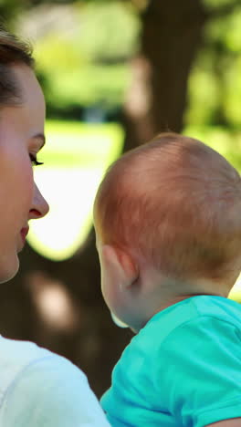 Madre-Sosteniendo-A-Un-Lindo-Hijo-En-El-Parque