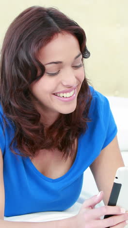 Smiling-woman-using-tablet-on-bed-