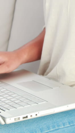 Smiling-woman-with-a-credit-card-and-a-laptop-on-a-sofa