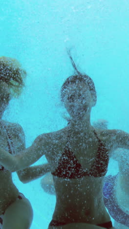 Four-friends-jumping-into-swimming-pool-and-waving