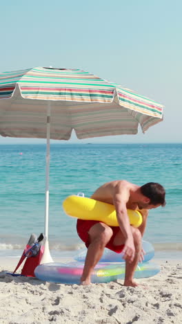 Hombre-Feliz-Tumbado-En-La-Playa-Con-Anillo-De-Goma-