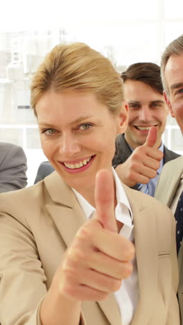 Business-people-giving-thumbs-up-to-camera