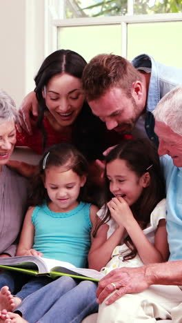 Lächelnde-Familie,-Die-Gemeinsam-Ein-Buch-Auf-Dem-Sofa-Liest