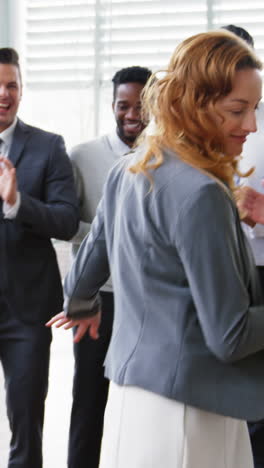 Businesswoman-dancing-while-her-colleagues-applauding-