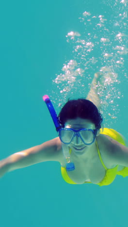 Pretty-brunette-diving-into-swimming-pool-wearing-snorkel