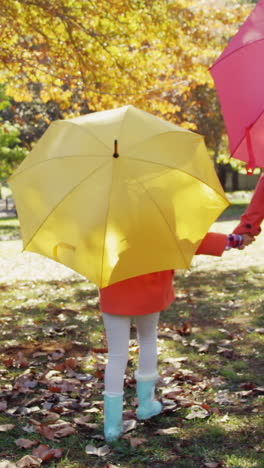 mother-and-daughter-walking-outdoors-with-umbrellas