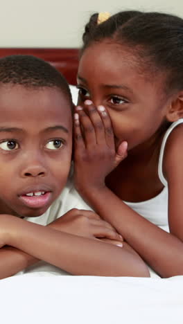 Cute-siblings-whispering-in-bed