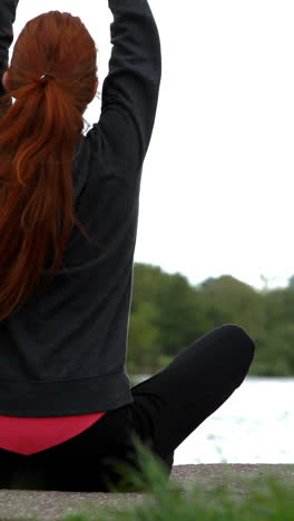 Calm-redhead-doing-yoga-by-a-lake-