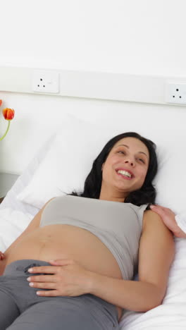 Brunette-pregnant-woman-lying-on-bed-talking-with-partner-and-doctor