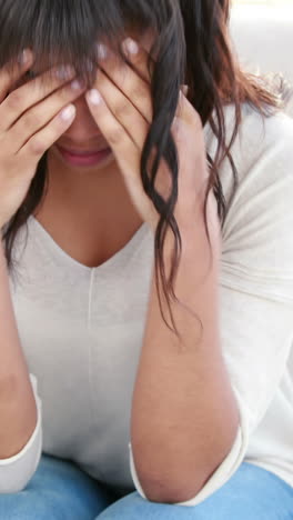 Stressed-woman-holding-her-head-on-couch-