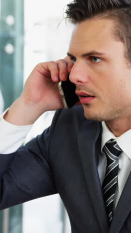 Businessman-picking-up-a-call-while-working-in-laptop