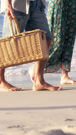 Mid-section-of-mature-couple-walking-on-the-sand