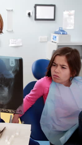 Pediatric-dentist-showing-x-ray-to-little-girl