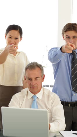 Business-team-in-front-of-laptop-then-pointing-to-camera