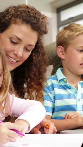 Happy-children-drawing-at-the-table-with-their-parents-and-using-laptop