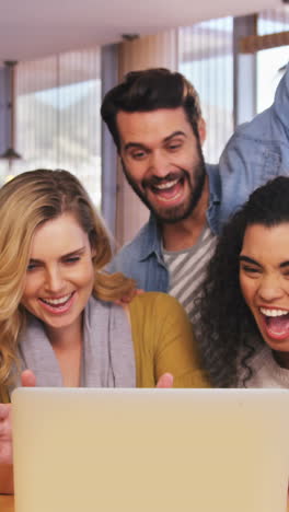 Smiling-friends-using-laptop-in-cafÃ©