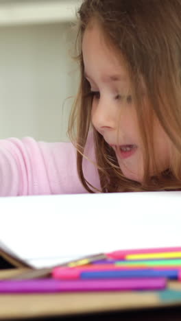 Little-girl-drawing-at-the-kitchen-table-and-smiling-at-camera