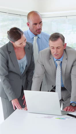 Business-people-looking-at-laptop-computer-during-meeting