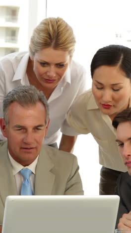 Positive-business-team-discussing-something-on-the-laptop