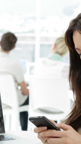 Mujer-Trabajando-En-Su-Escritorio-Enviando-Mensajes-De-Texto-Por-Teléfono