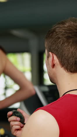 Male-trainer-checking-treadmill-performance