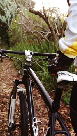 Mountain-biking-couple-walking-on-forest-trail-with-bike