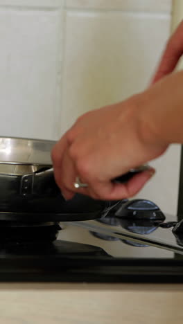 Woman-cooking-something-in-frying-pan-at-the-stove-top