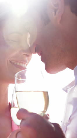 Happy-couple-romancing-while-having-a-glass-of-wine-in-field