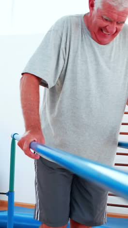 Smiling-physiotherapist-helping-patient-walk-with-parallel-bars