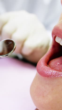 Dentist-examining-a-female-patient-with-tools