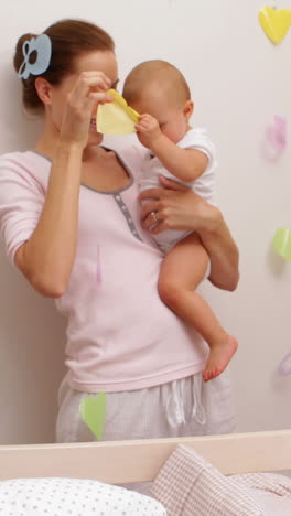 Mother-holding-her-baby-daughter-and-playing-with-mobile