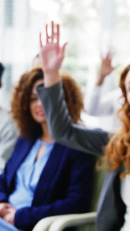 Businesspeople-raising-their-hands-during-a-meeting-