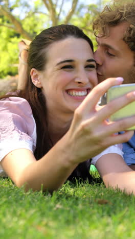 Una-Pareja-Tumbada-En-El-Césped-Tomándose-Un-Selfie