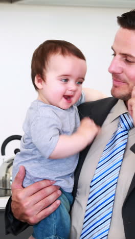 Father-holding-his-baby-son-before-work-and-talking-on-phone