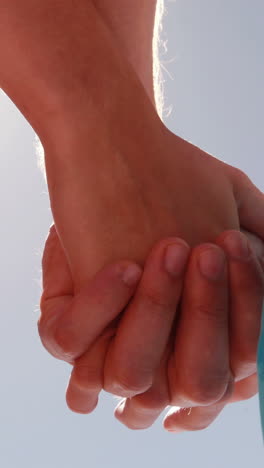 Couple-standing-hand-in-hand-on-the-beach