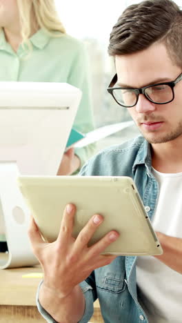 Casual-businessman-using-tablet-in-front-of-colleagues