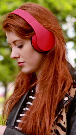 Pretty-redhead-listening-to-music-in-the-park-