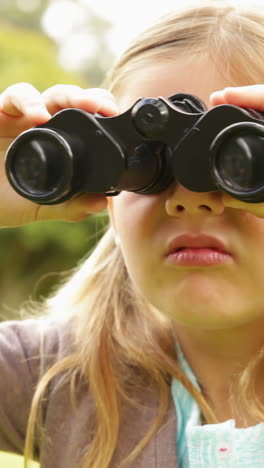 Cute-little-girl-using-binoculars-in-park