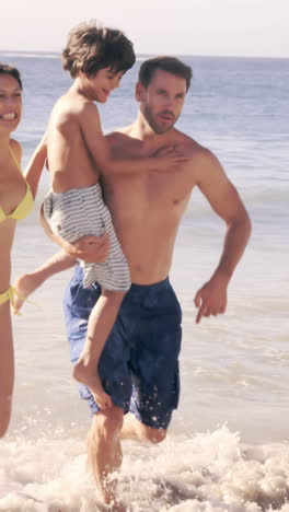 Cute-family-running-out-of-the-water-on-the-beach