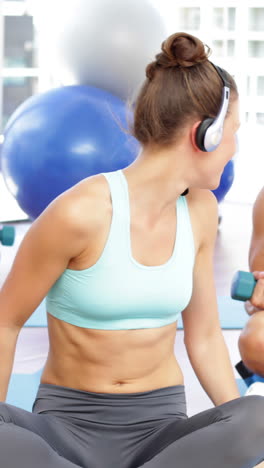 Fitness-class-sitting-together-and-lifting-dumbbells