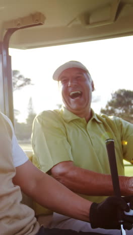 Two-golfers-laughing-together-in-their-golf-buggy