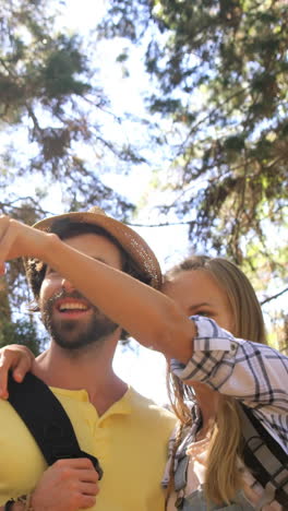 Pareja-De-Excursionistas-De-Pie-Y-Apuntando-Hacia-El-Bosque