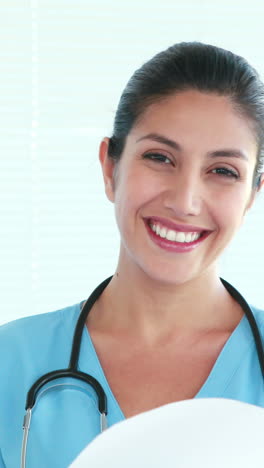 Happy-doctor-holding-clipboard-and-looking-at-camera