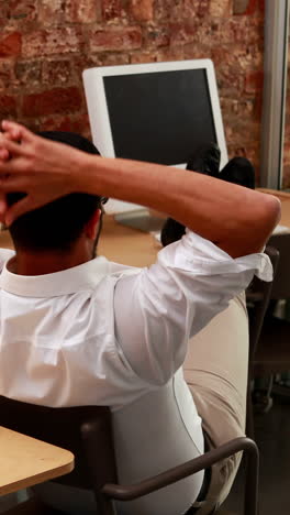 Casual-businessman-relaxing-at-desk-leaning-back