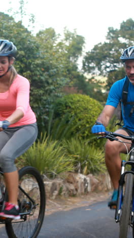 Couple-interacting-while-riding-bicycle-on-road