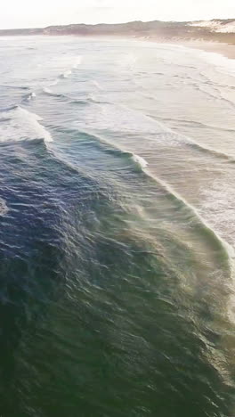 Aerial-view-of-waves-reaching-a-shore-at-beach