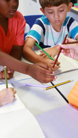 Teacher-helping-kids-with-their-homework-in-classroom