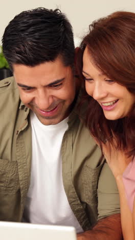 Young-couple-chatting-and-looking-at-laptop