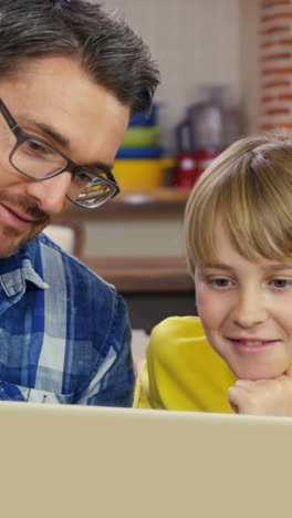 Smiling-father-and-son-using-laptop