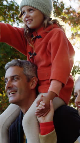 Girl-on-dads-back-with-mom-walking-outdoors